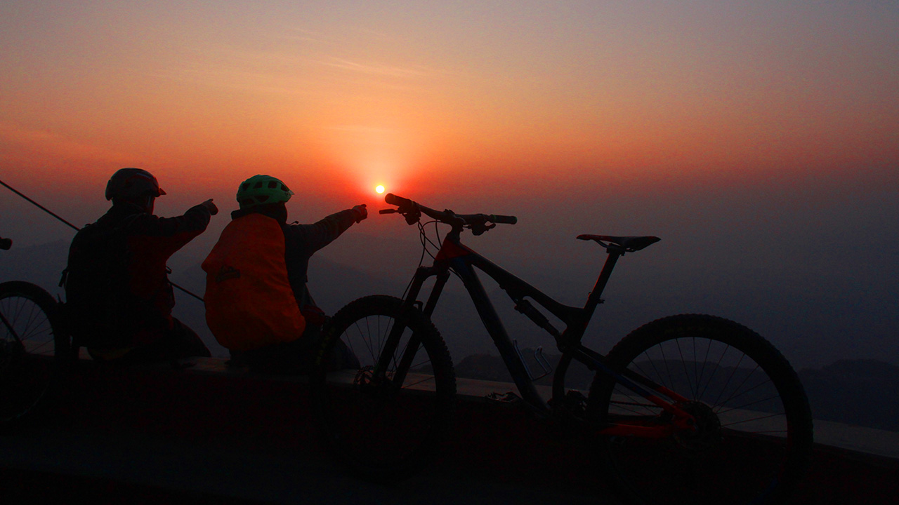 Two mountain bikers are enjoying the view of sunrise from Sarangkot.