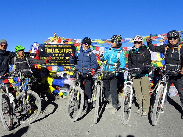 Group of mountain bikers posing for a picture on the top of Thorong-La pass.