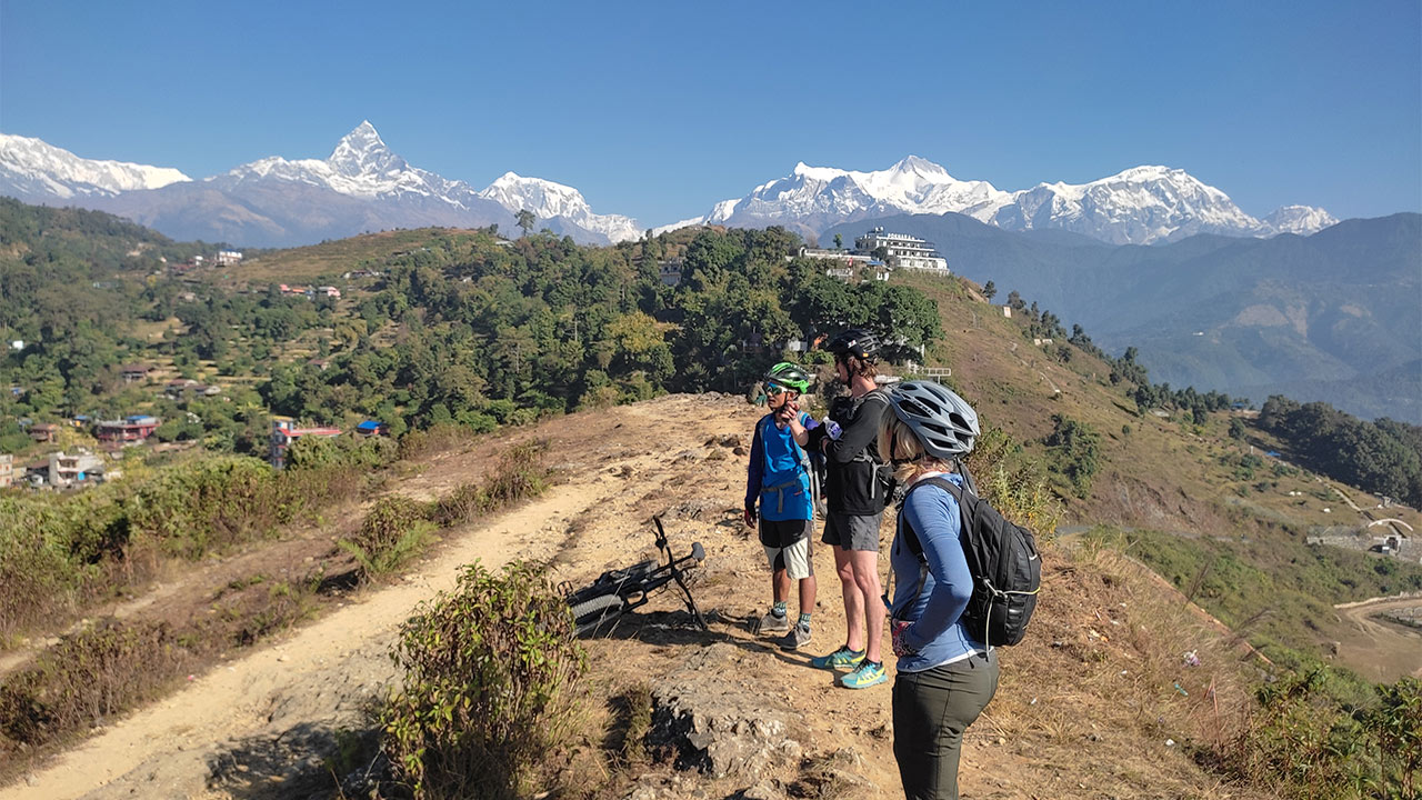 Three mountain bikers stopping to observe the views of the Annapurna Himalayan range and the surrounding 