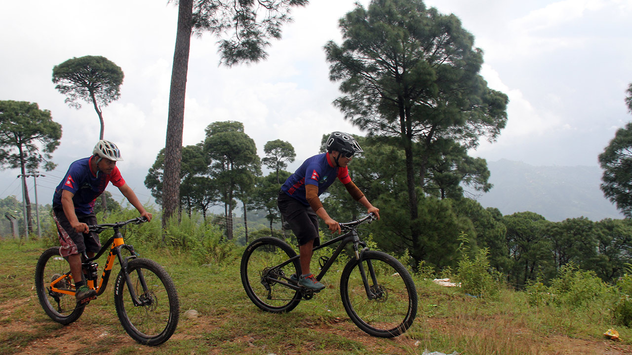 Mountain bikers imprinted with the flag of Nepal on their jersey's shoulder are enjoying their ride towards Dhading
