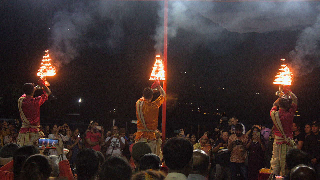 Crowd of people watching three priests performing aarati on the Lake shore of Pokhara, Barahi temple