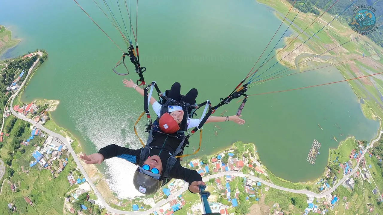 A pilot raises his selfie pole to take picture above Phewa Lake during the paragliding tandem flight in Pokhara.