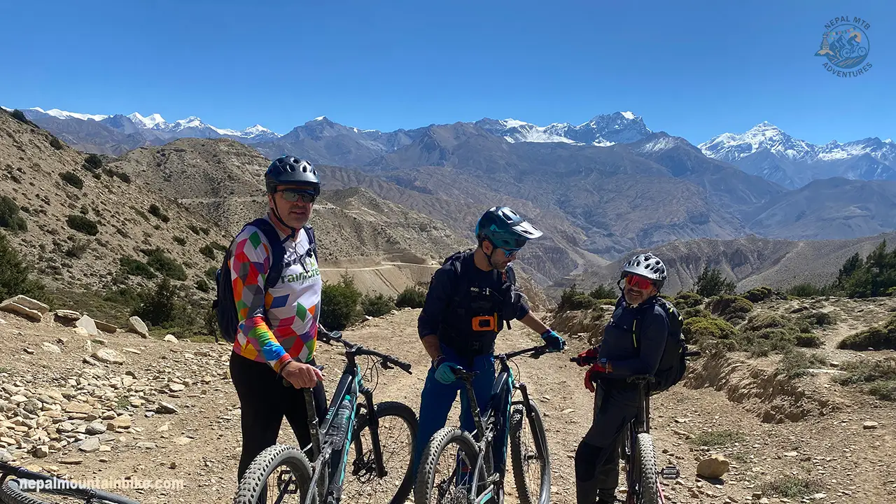 Electric mountain bike rider in Upper Mustang, Nepal beneath the Himalayas.