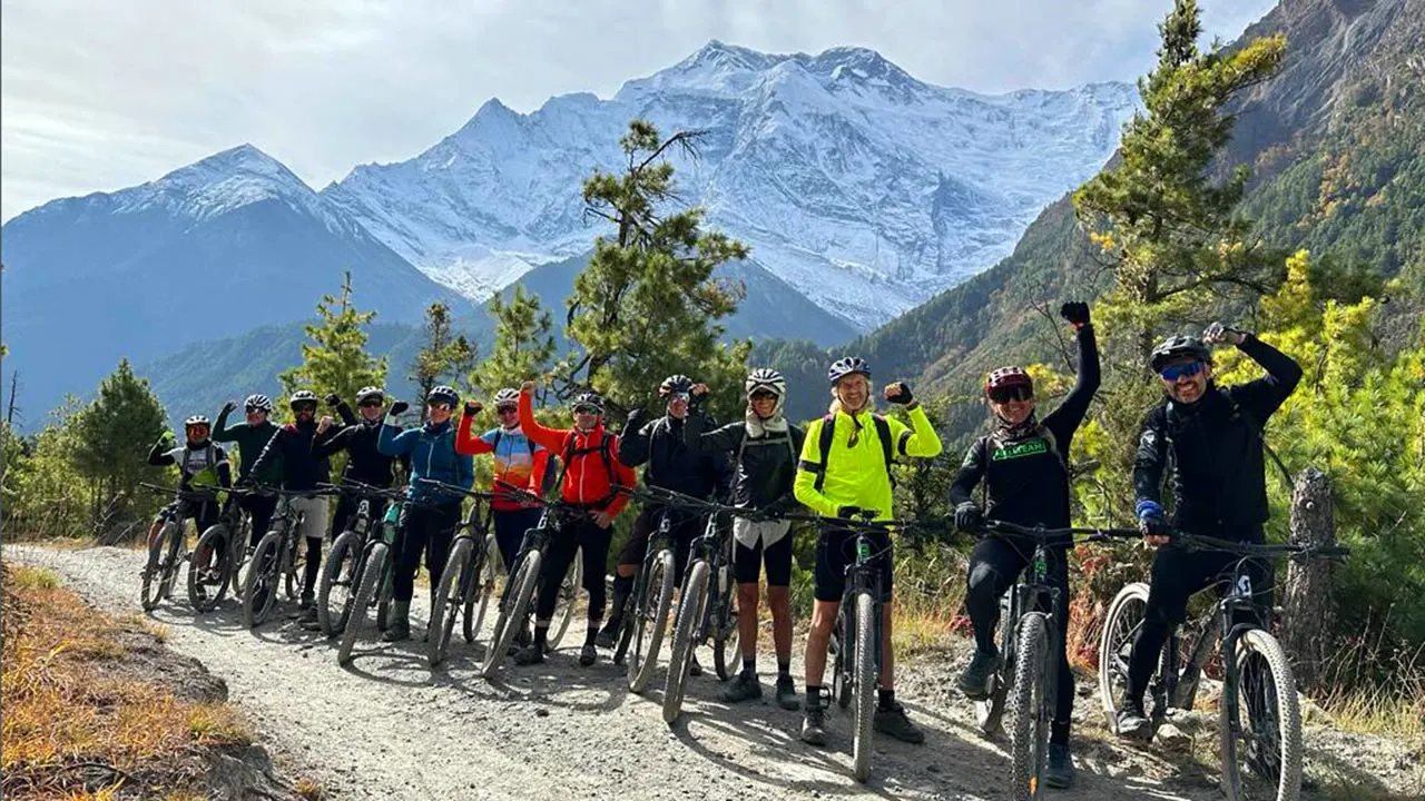 Group of mountain bikers taking picture with the backdrop of Annapurna I during the Annapurna Circuit guided MTB tour in Nepal.