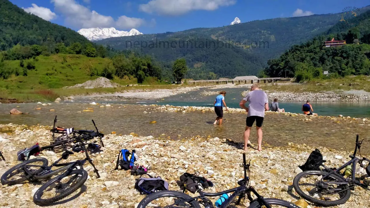 Mountain bikers refreshing in the Harpan River during the guided one day MTB tour in Pokhara.