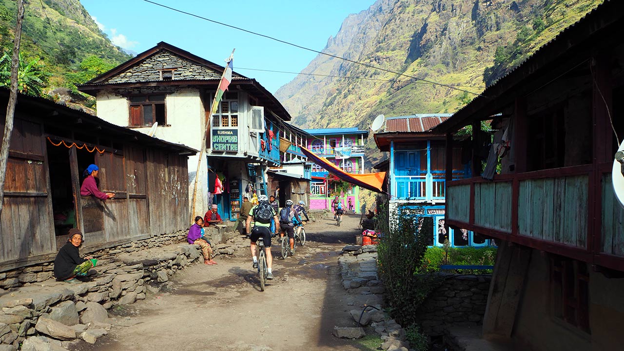 A group of mountain bikers on their mountain bikes are on the way to Manang, passing through the colorful village of Jagat while greeting Namaste to friendly locals.