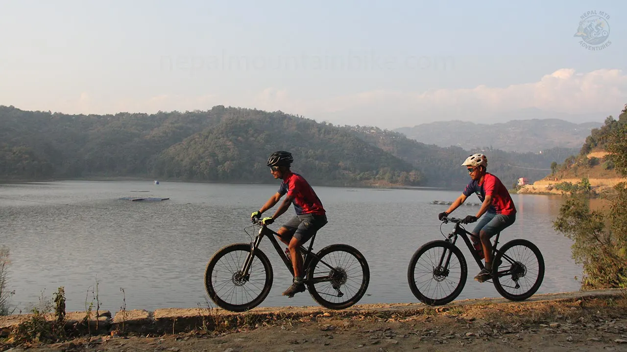 Mountain bikers enjoying the ride along the lake during the overnight guided day tour in Pokhara.