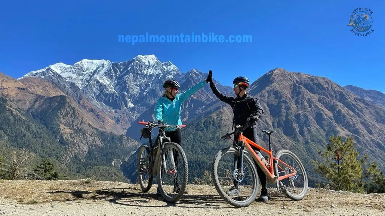 A couple high-fiving with the background of Nilgiri South during Lower Mustang mountain biking tour in Nepal.