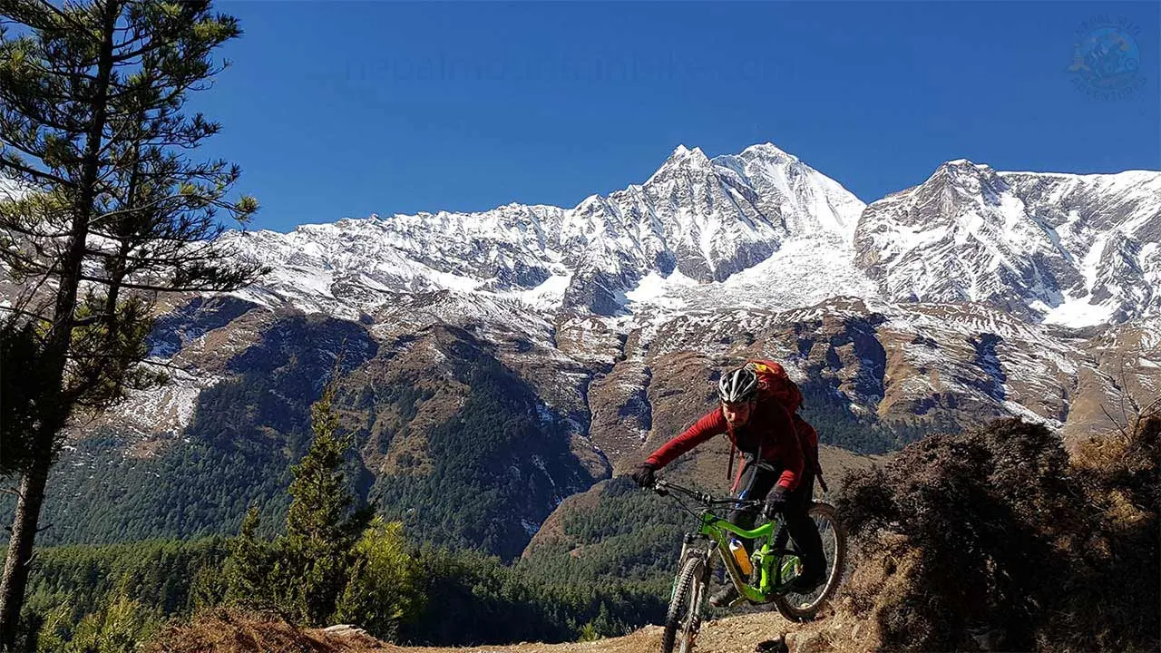 MTB biker descends the rugged terrain of Mustang on his full suspension bike with the Dhaulagiri forming a backdrop.