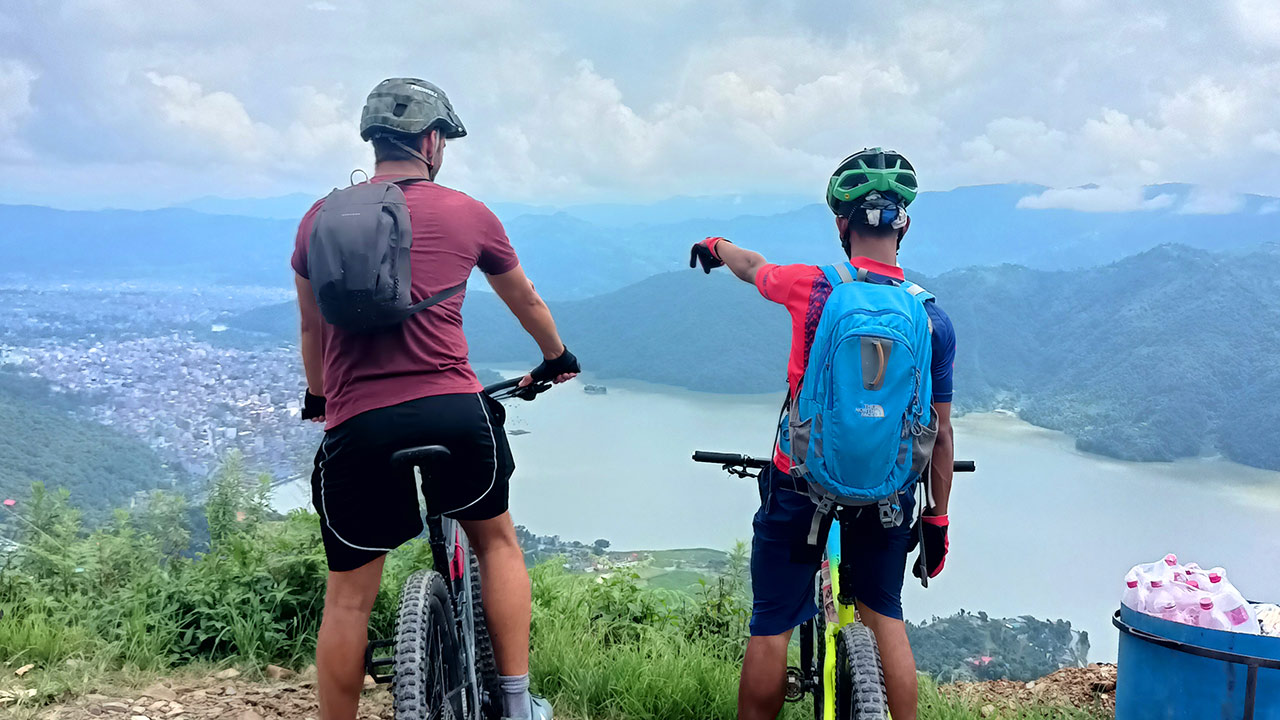 Mountain bikers are observing the view of Fewa Lake and Pokhara valley during their bike tour to Sarangkot.