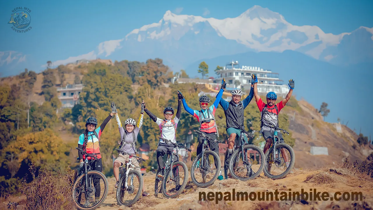 Group of mountain bikers cheering with joy during Sarangkot mountain bike tour in Pokhara, Nepal.