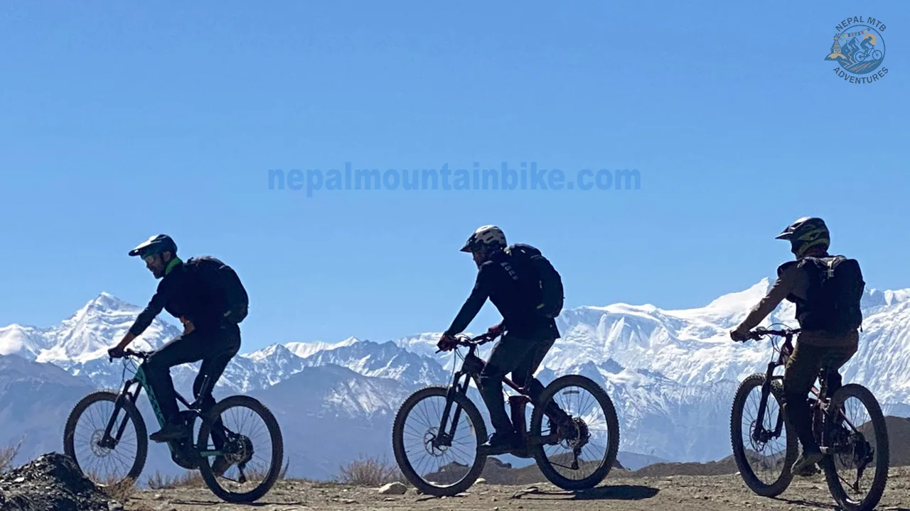 Three mountain bikers are riding -E-MTBs with the views of Himalayas during Mustang E-bike tour in Nepal.