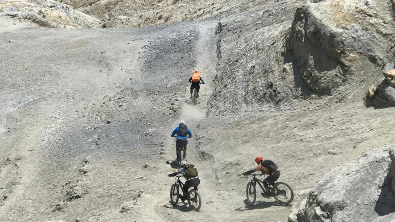 Four mountain bikers are descending down through steep trail on their mountain bike in Upper Mustang.