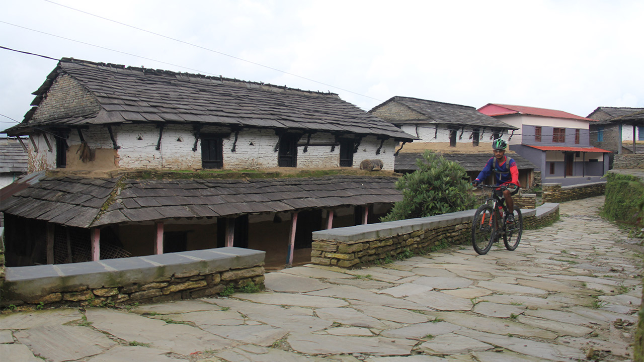 A biker rides his mountain bike through Gurung village in Dhampus.