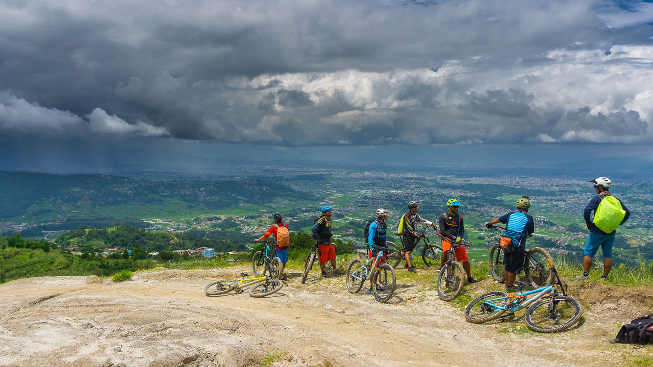 Group of mountain bikers observing the view of Kathmandu valley during mountain bike tour in Nepal.