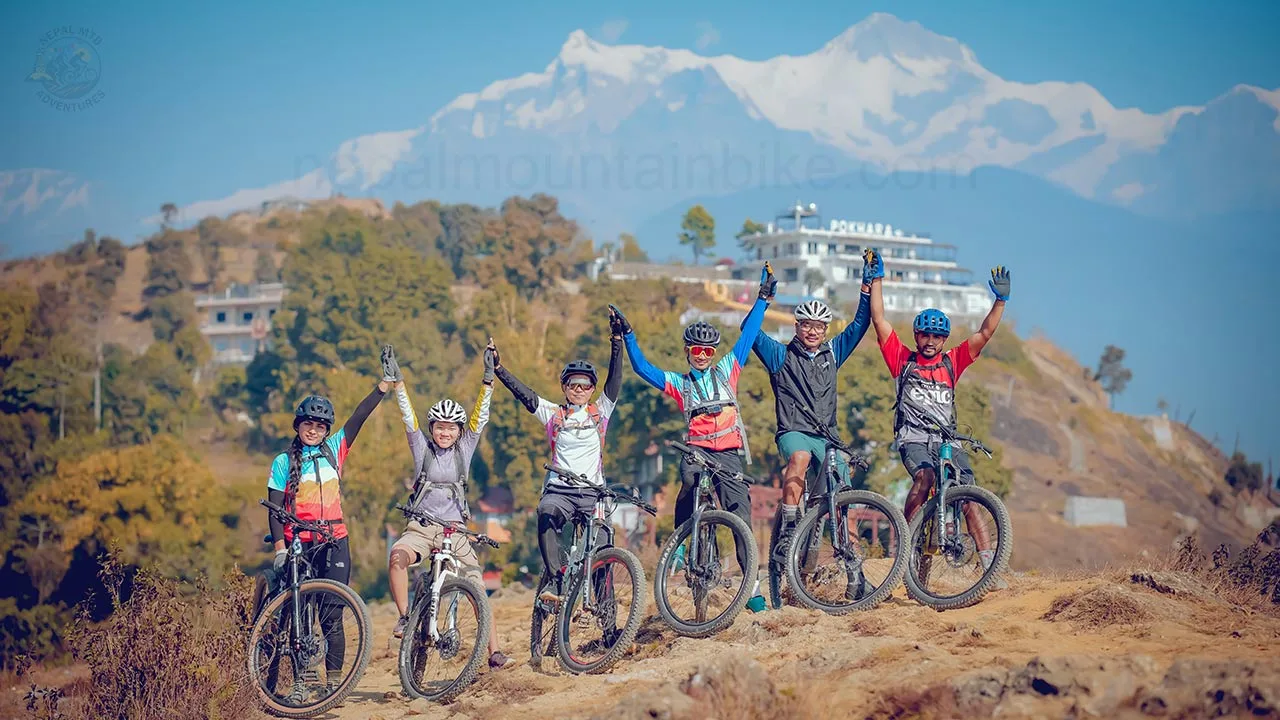 Mountain bikers posing for a picture with their hands raised during one day guided mountain bike tour in Pokhara.