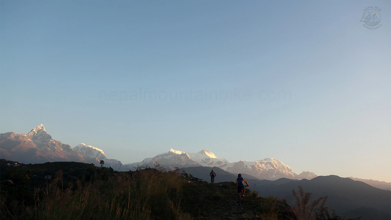 Mountain bikers riding their bikes with the view of the Himalayas during the one day MTB tour to Sarangkot in Pokhara.
